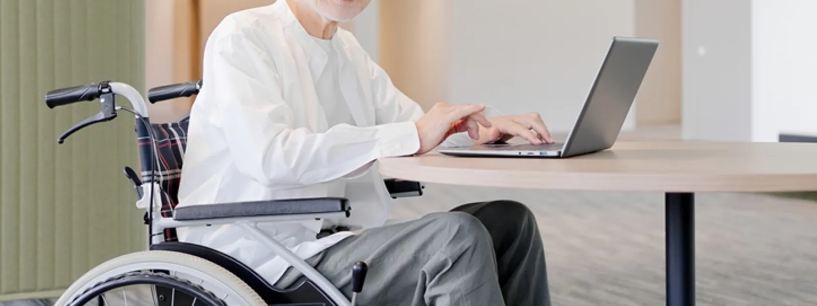 車椅子に乗った男性がパソコンを操作している様子
